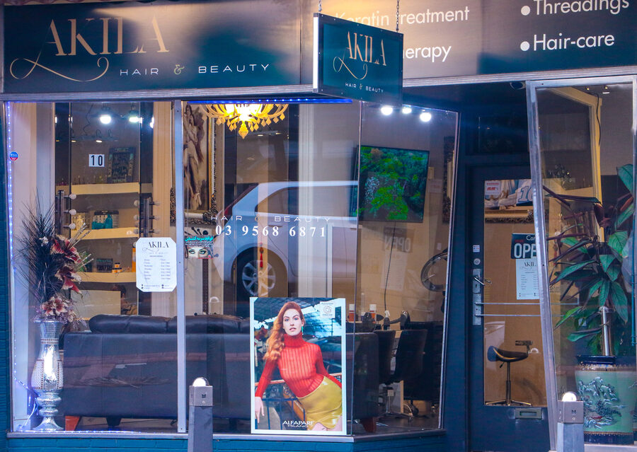The front of Akila Hair and Beauty at 10 Station Street, Oakleigh, at dusk: the sign lit above the window